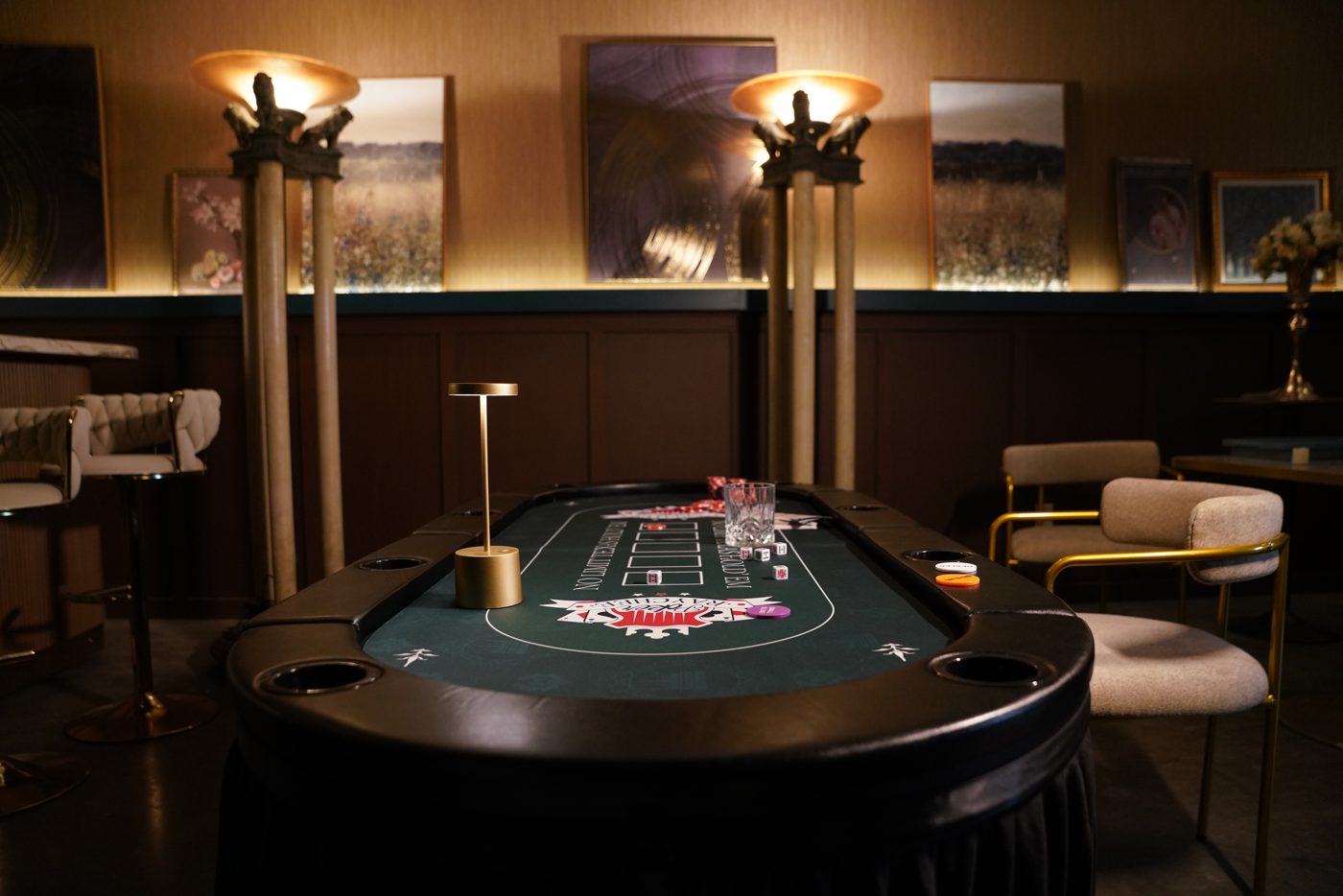 Casino lux bar standing set: a poker table under two glowing floor lamps, with bar stools, gold-framed chairs and warm wood walls